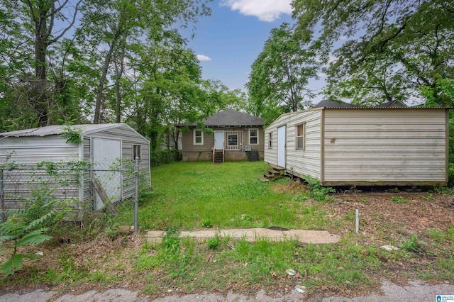 view of green lawn with a storage shed, entry steps, and an outdoor structure