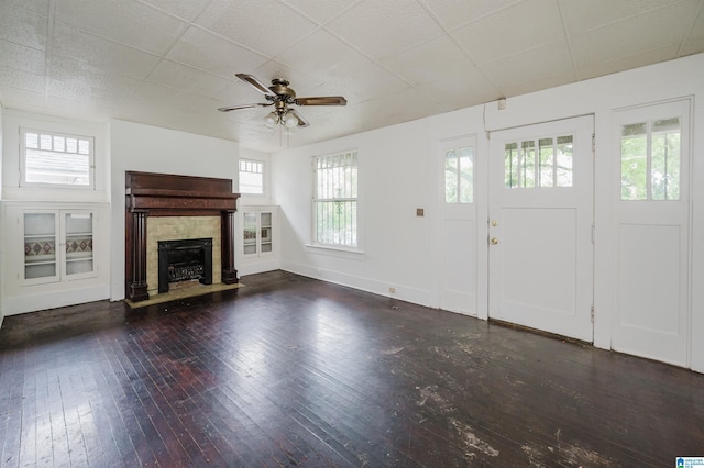 unfurnished living room with plenty of natural light, hardwood / wood-style floors, ceiling fan, and a tiled fireplace