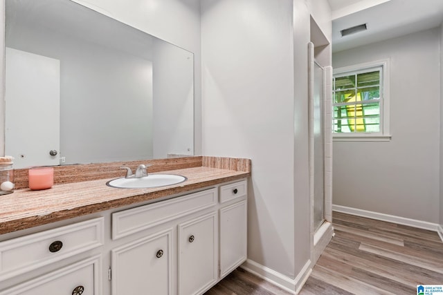 full bath with wood finished floors, vanity, an enclosed shower, and baseboards