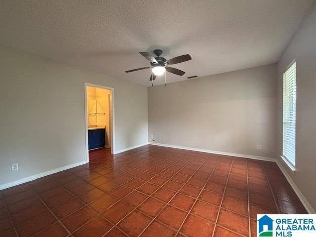 7601 Meadows Dr S, Mobile, AL 36619 - empty room with ceiling fan, dark tile patterned flooring, baseboards, and a textured ceiling