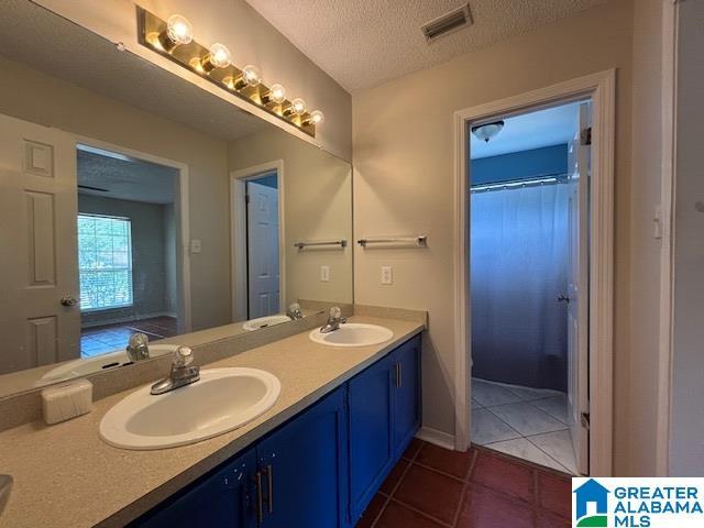 7601 Meadows Dr S, Mobile, AL 36619 - bathroom with double vanity, tile patterned floors, and a textured ceiling