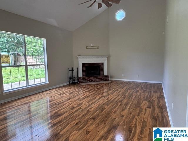 7601 Meadows Dr S, Mobile, AL 36619 - unfurnished living room featuring ceiling fan, wood finished floors, baseboards, a fireplace, and high vaulted ceiling