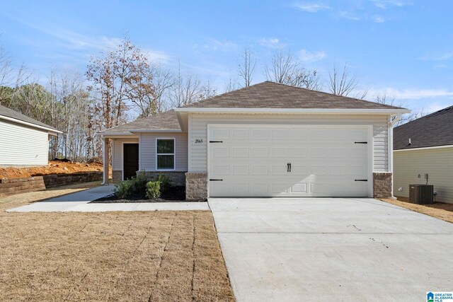 view of front of house with stone siding, central AC, concrete driveway, a shingled roof, and an attached garage