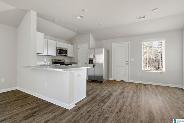 kitchen featuring stainless steel appliances, light countertops, wood finished floors, white cabinetry, and a peninsula