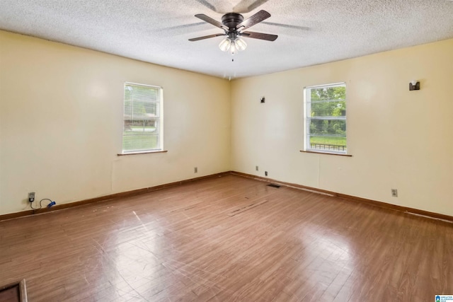 empty room featuring a ceiling fan, wood finished floors, a textured ceiling, and baseboards
