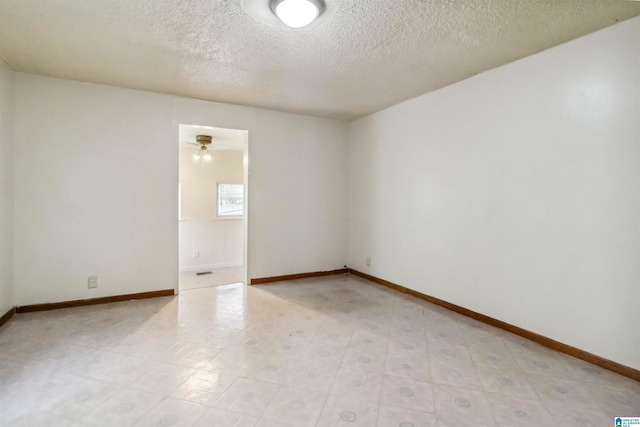 unfurnished room featuring a textured ceiling and baseboards