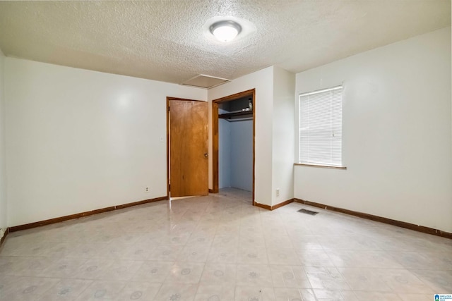 unfurnished bedroom featuring a textured ceiling, attic access, baseboards, and a closet