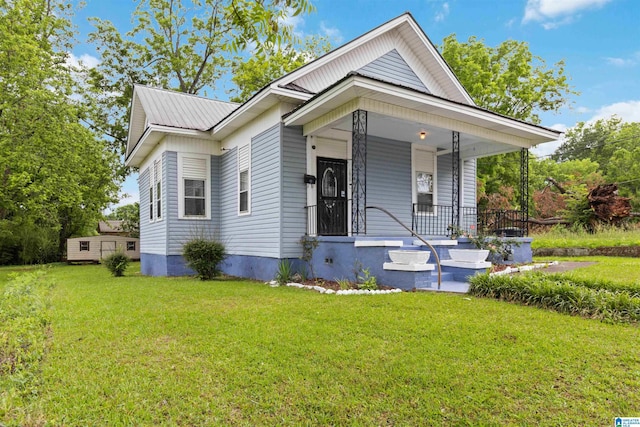 view of front of home featuring a front yard, a porch, and metal roof
