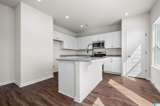 2017 Valley Run, Leeds, AL 35094 - kitchen featuring appliances with stainless steel finishes, light stone countertops, dark wood finished floors, white cabinetry, and a center island with sink