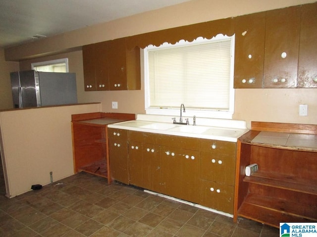 1782 49th St, Birmingham, AL 35208 - kitchen with freestanding refrigerator, a sink, brown cabinets, and plenty of natural light