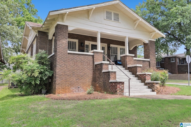 view of front facade with brick siding, a front yard, and stairway