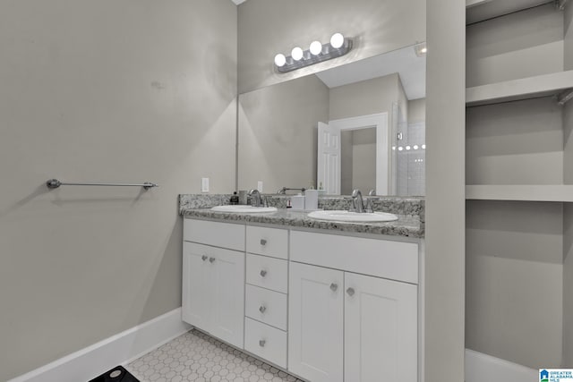 full bathroom featuring baseboards and double vanity