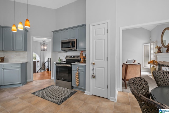 126 Landale Dr, Sterrett, AL 35147 - kitchen featuring appliances with stainless steel finishes, gray cabinetry, a towering ceiling, tasteful backsplash, and hanging light fixtures