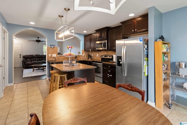 22873 Downing Park Cir, Mccalla, AL 35111 - kitchen featuring stainless steel appliances, arched walkways, dark brown cabinets, backsplash, and hanging light fixtures