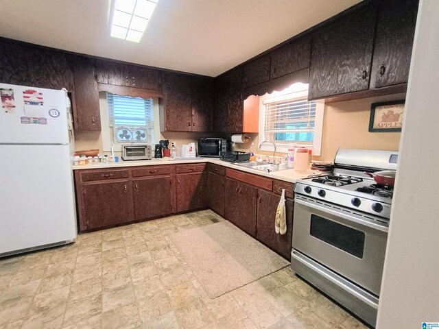 335 Shady Hollow Ln, Talladega, AL 35160 - kitchen featuring freestanding refrigerator, stainless steel gas stove, a sink, light countertops, and dark brown cabinetry