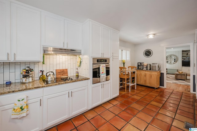 3309 Eaton Rd, Mountain Brook, AL 35223 - kitchen with oven, under cabinet range hood, black electric stovetop, white cabinetry, and tasteful backsplash