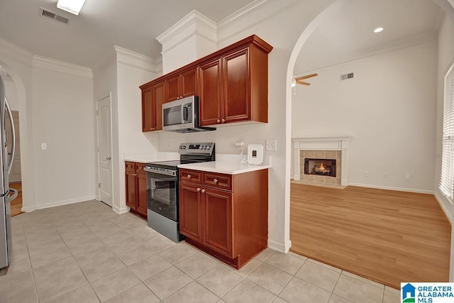 653 Talon Trce, Birmingham, AL 35242 - kitchen featuring stainless steel appliances, arched walkways, light tile patterned flooring, a tiled fireplace, and ceiling fan