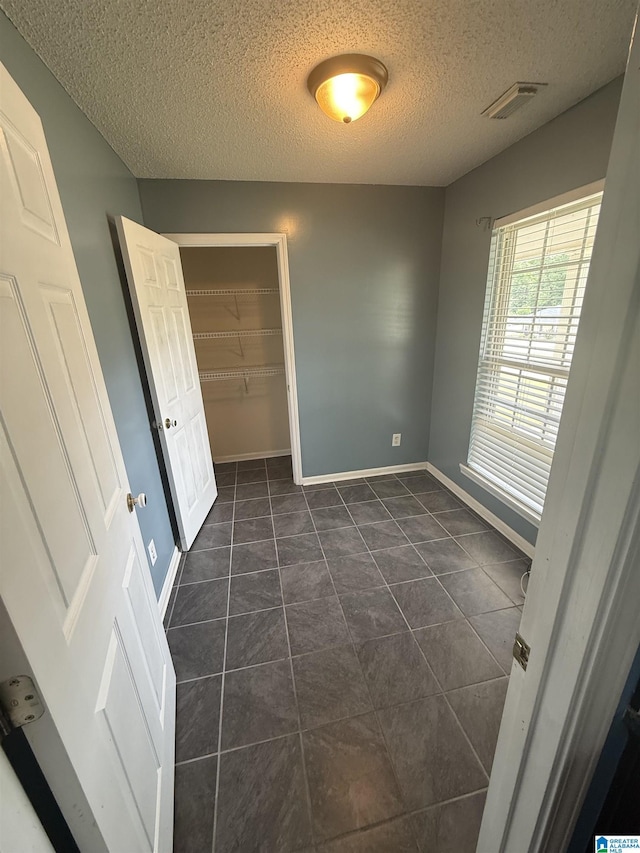 18470 Whispering Meadows Blvd, Vance, AL 35490 - unfurnished bedroom featuring a textured ceiling, baseboards, a closet, and dark tile patterned floors