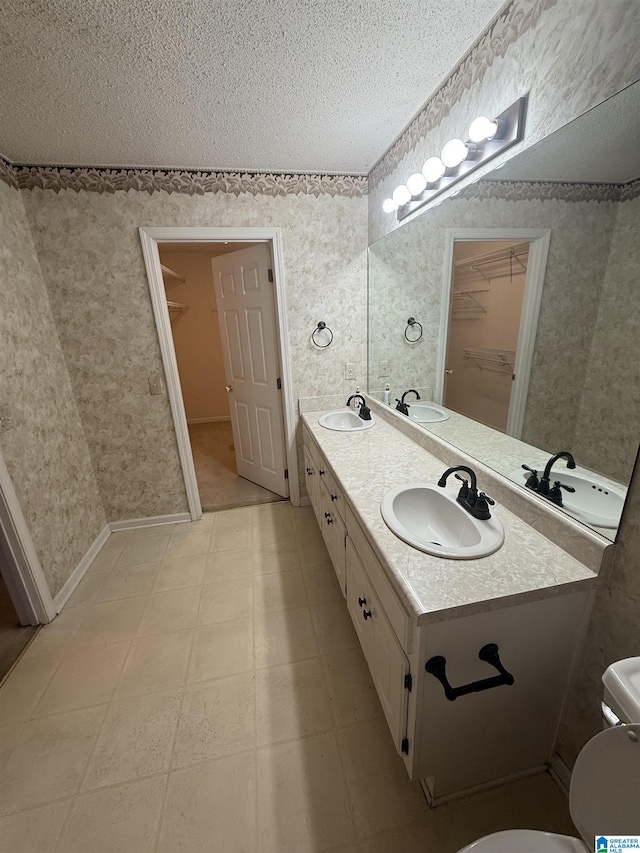 18470 Whispering Meadows Blvd, Vance, AL 35490 - full bathroom featuring a textured ceiling, a walk in closet, double vanity, toilet, and tile patterned floors