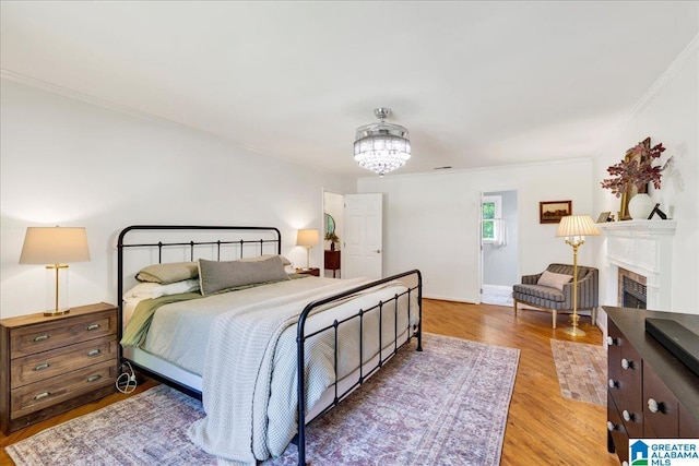 113 Pine Cliff Cir, Hoover, AL 35226 - bedroom featuring crown molding, wood finished floors, a fireplace, a chandelier, and baseboards