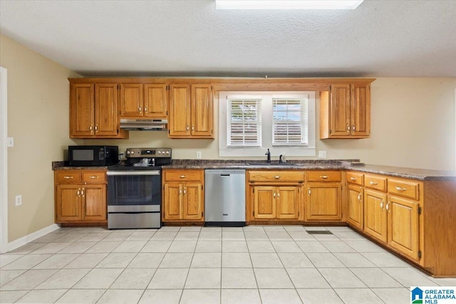 114NW Morgan Ave, Cullman, AL 35055 - kitchen featuring appliances with stainless steel finishes, a sink, under cabinet range hood, a peninsula, and brown cabinetry