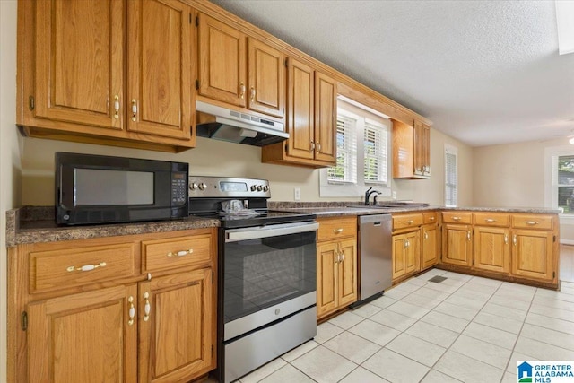 114NW Morgan Ave, Cullman, AL 35055 - kitchen with appliances with stainless steel finishes, under cabinet range hood, light tile patterned floors, a peninsula, and plenty of natural light