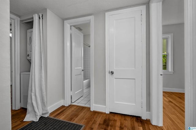 4763 7th Ct S, Birmingham, AL 35222 - unfurnished bedroom featuring stacked washer and clothes dryer, wood finished floors, baseboards, connected bathroom, and a textured ceiling