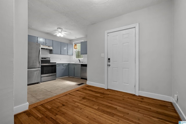 4763 7th Ct S, Birmingham, AL 35222 - kitchen with appliances with stainless steel finishes, under cabinet range hood, gray cabinetry, light wood-type flooring, and a ceiling fan