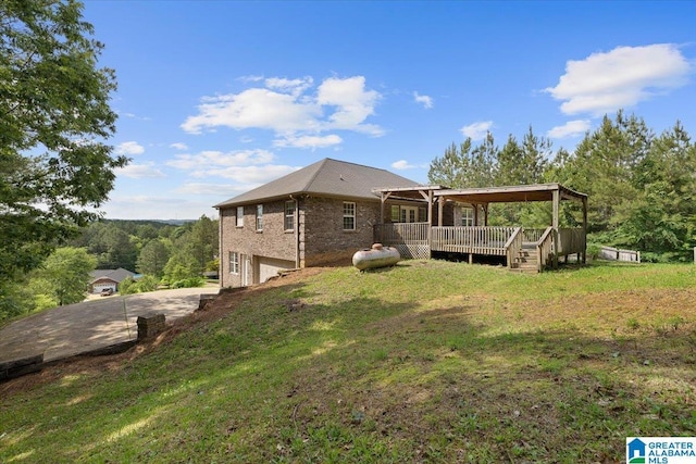 255 Savannah Ln, Cleveland, AL 35049 - rear view of property featuring an attached garage, a wooden deck, concrete driveway, brick siding, and a yard