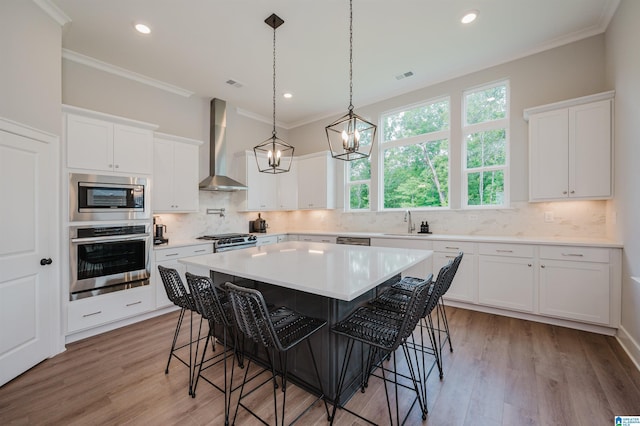 4651 Silas Ave, Hoover, AL 35244 - kitchen featuring stainless steel appliances, wall chimney exhaust hood, a kitchen bar, crown molding, and a sink