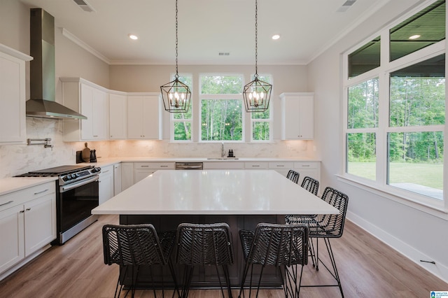 4651 Silas Ave, Hoover, AL 35244 - kitchen featuring wall chimney exhaust hood, stainless steel range, a kitchen bar, crown molding, and light wood-type flooring