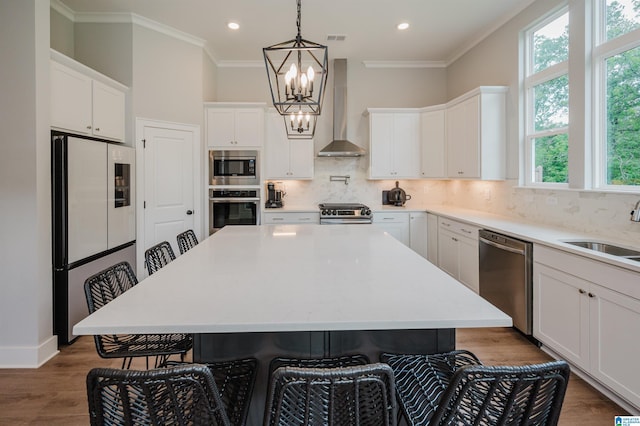 4651 Silas Ave, Hoover, AL 35244 - kitchen featuring appliances with stainless steel finishes, wall chimney exhaust hood, a sink, a chandelier, and a kitchen breakfast bar