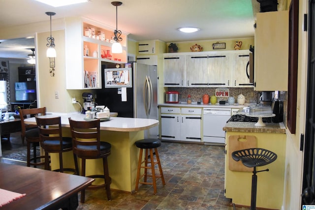 3908 Cloverdale Rd, Anniston, AL 36207 - kitchen with white dishwasher, a peninsula, freestanding refrigerator, tasteful backsplash, and dark stone finish flooring