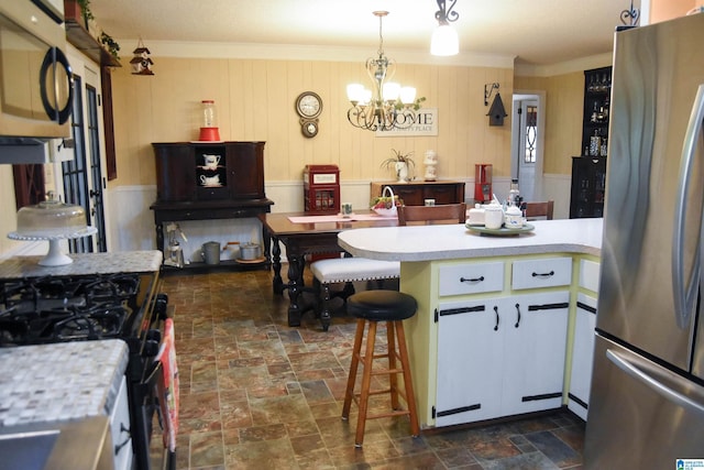 3908 Cloverdale Rd, Anniston, AL 36207 - kitchen featuring appliances with stainless steel finishes, a chandelier, light countertops, dark stone finish floors, and white cabinetry