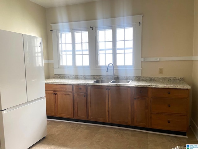 1428 11th Pl S, Birmingham, AL 35205 - kitchen with freestanding refrigerator, a sink, brown cabinetry, and healthy amount of natural light