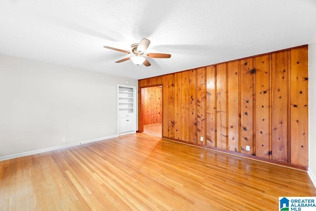 4010 93rd St, Northport, AL 35473 - spare room with ceiling fan, light wood finished floors, baseboards, wooden walls, and a textured ceiling