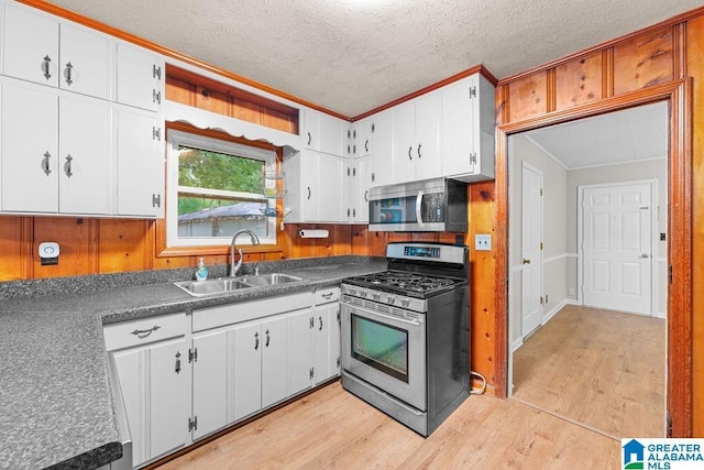 4010 93rd St, Northport, AL 35473 - kitchen featuring stainless steel appliances, a sink, crown molding, a textured ceiling, and light wood-style flooring