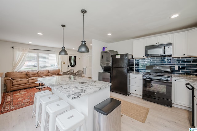 1320 Monticello St, Irondale, AL 35210 - kitchen featuring black appliances, light wood finished floors, white cabinets, open floor plan, and tasteful backsplash