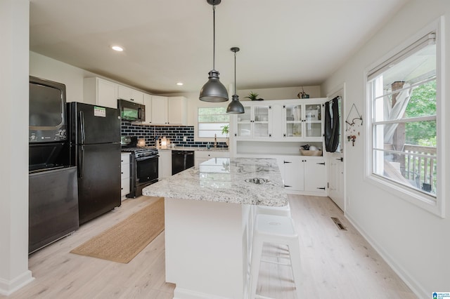 1320 Monticello St, Irondale, AL 35210 - kitchen featuring black appliances, light wood finished floors, a center island, white cabinetry, and recessed lighting