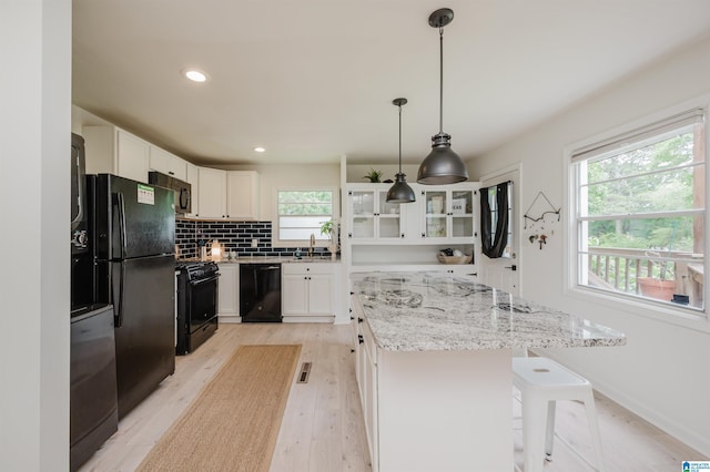 1320 Monticello St, Irondale, AL 35210 - kitchen with black appliances, a kitchen island, light wood-style flooring, white cabinets, and recessed lighting