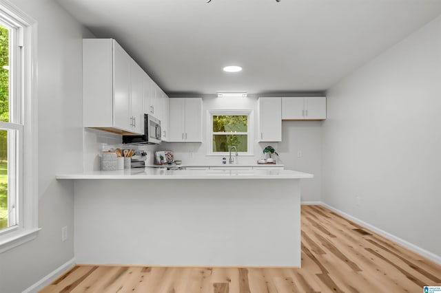 941 Honeysuckle Ln, Moody, AL 35094 - kitchen with appliances with stainless steel finishes, a peninsula, light wood-type flooring, light countertops, and baseboards
