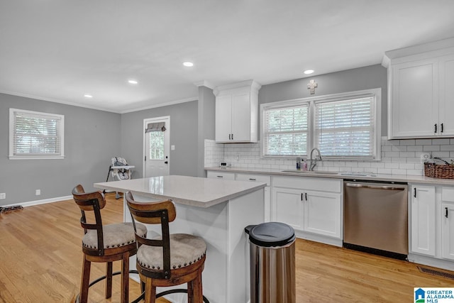 1115 Park Ave, Oneonta, AL 35121 - kitchen featuring stainless steel dishwasher, a sink, a kitchen bar, crown molding, and light wood-type flooring