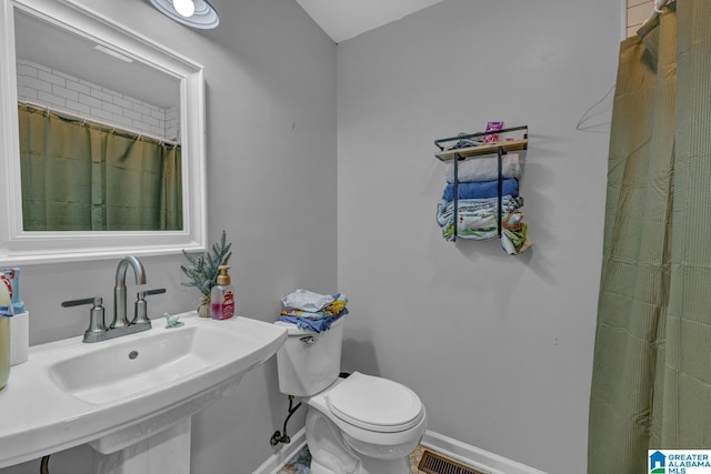 1115 Park Ave, Oneonta, AL 35121 - bathroom featuring toilet, baseboards, a sink, and a shower with shower curtain