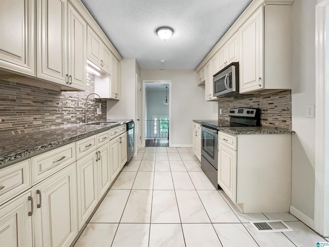 1012 Christopher Dr, Birmingham, AL 35215 - kitchen with stainless steel appliances, a sink, decorative backsplash, a textured ceiling, and dark stone countertops