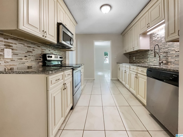 1012 Christopher Dr, Birmingham, AL 35215 - kitchen with appliances with stainless steel finishes, tasteful backsplash, cream cabinetry, light tile patterned flooring, and a textured ceiling