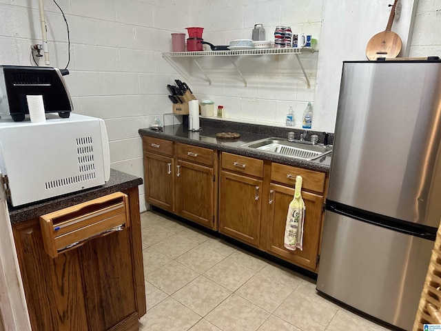 12325 US Highway 411 N, Centre, AL 35960 - kitchen with freestanding refrigerator, a sink, light tile patterned flooring, brown cabinetry, and dark stone counters