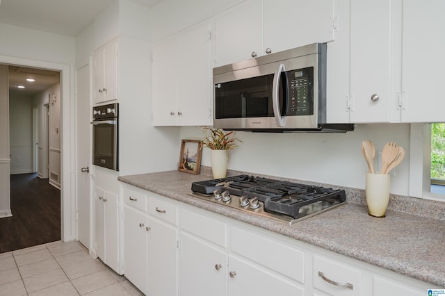 732 Highland Ave, Birmingham, AL 35206 - kitchen with appliances with stainless steel finishes, white cabinets, light countertops, and light tile patterned floors