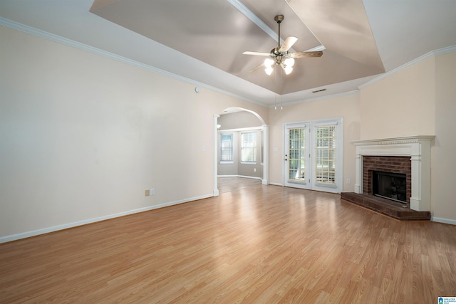 4244 Cobblestone Ct, Pinson, AL 35126 - unfurnished living room featuring a ceiling fan, arched walkways, light wood-style floors, baseboards, and a tray ceiling