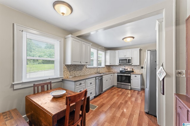 784 80th St, Birmingham, AL 35206 - kitchen featuring appliances with stainless steel finishes, a sink, backsplash, and light wood-style floors