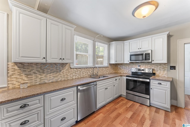 784 80th St, Birmingham, AL 35206 - kitchen featuring stainless steel appliances, a sink, light wood-type flooring, and tasteful backsplash